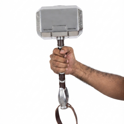 A hand holding a miniature replica of Thor's hammer, Mjolnir, featuring a silver metallic head, brown leather-wrapped handle, and silver wrist strap, isolated on a white background.