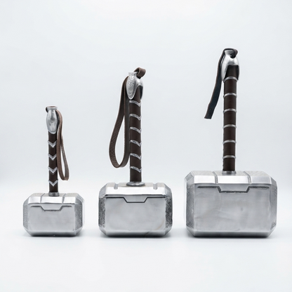 Three Thor's Hammer (Mjolnfr) prop toys in different sizes, arranged from smallest to largest on a seamless white studio background. 